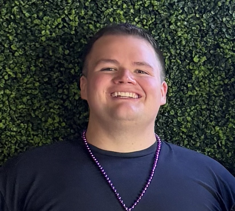 Stephen Daneker, founder of Heartland Insights, smiling in front of a green hedge wall